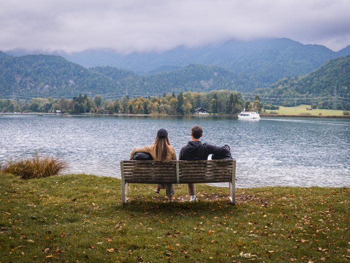 Ein Paar genie&szlig;t auf einer Bank am Wasser den Blick &uuml;ber den Kochelsee., &copy; T&ouml;lzer Land  Tourismus|Christian Geigl
